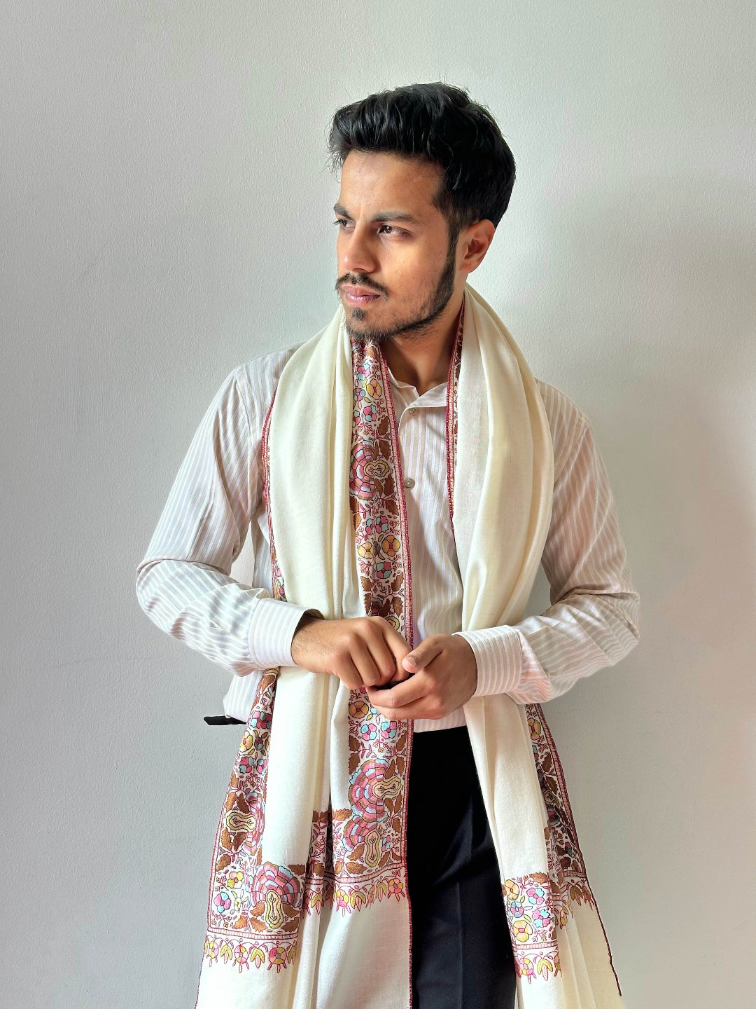 Man wearing a patterned scarf and formal attire against a plain background